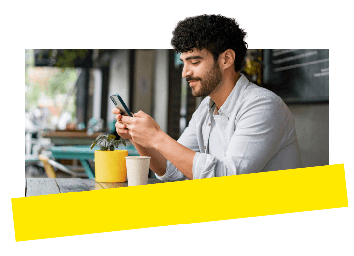 Professional enjoying GoTo's award winning business phone system on their mobile device while sitting outdoors at a cafe.