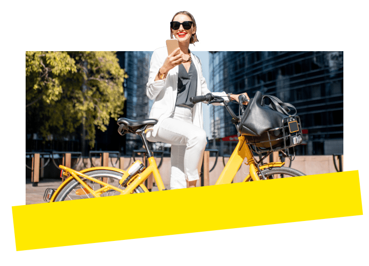 Professional taking a break from a bike ride, with a city skyline backdrop, using the GoTo Connect mobile app to connect from anywhere.